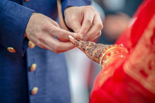 Free Close-up of couple exchanging rings with intricate henna designs in vibrant traditional attire. Stock Photo