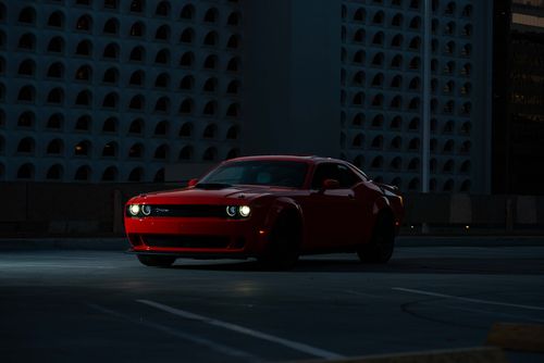 Free A sleek red sports car parked in an urban setting at night, exuding luxury and style. Stock Photo
