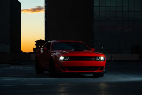 Free Striking red sports car captured at sunset in a city setting, emphasizing elegance and performance. Stock Photo