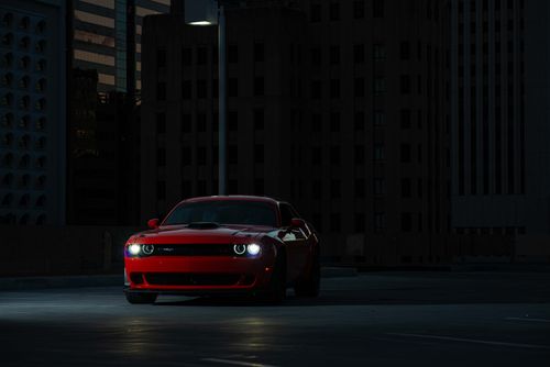 Free Dramatic shot of a red sports car parked at night in an urban setting, illuminated by streetlight. Stock Photo
