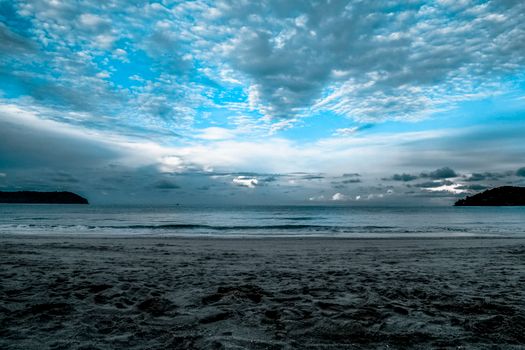 Serene beach with dramatic cloudscape at twilight, capturing a peaceful ocean view.