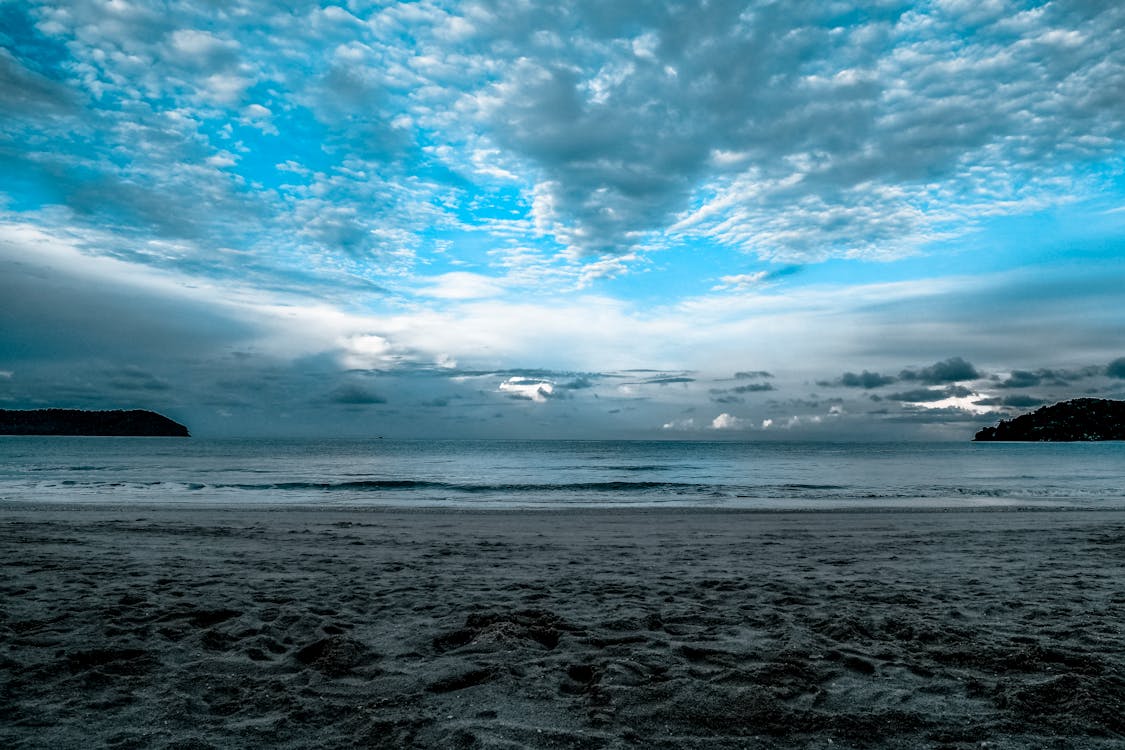 免费 白天在海边在多云的天空下的灰色沙子 素材图片