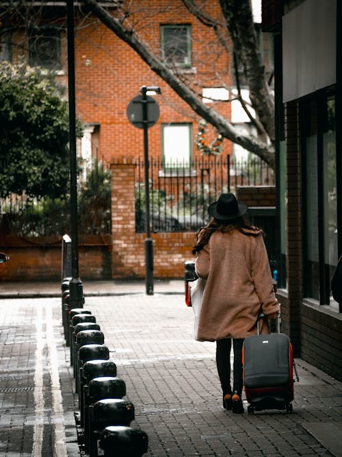 Woman in Brown Coat Holding a Luggage 