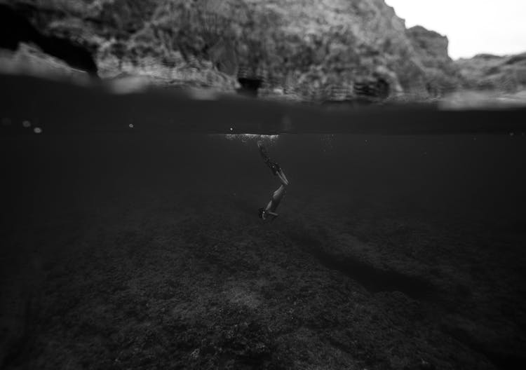 A Grayscale Photo Of A Person Diving On Water