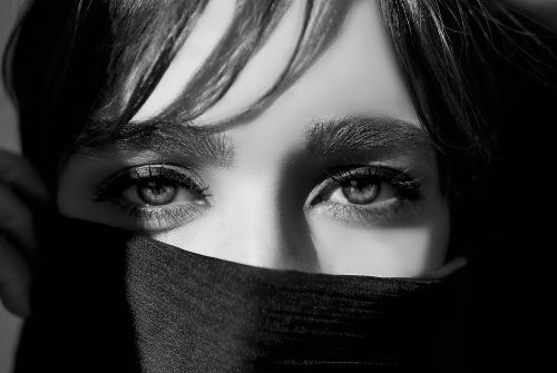 Free Intense black and white close-up of a woman's eyes, partially covered by fabric, in a dramatic and moody style. Stock Photo