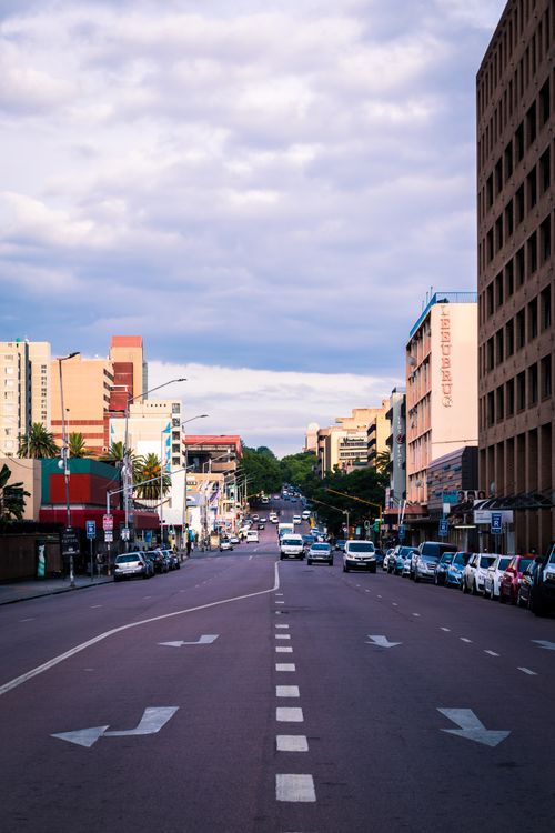 Free Busy city street with cars and buildings under a blue sky with white clouds. Stock Photo