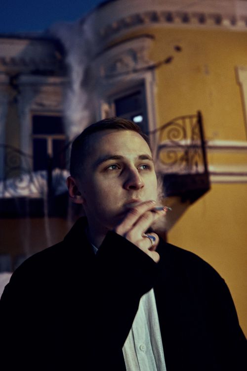 Free Portrait of a young adult smoking in an urban setting at night, with dramatic lighting. Stock Photo