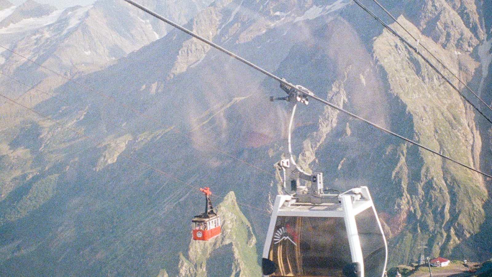 Cable cars climbing above a steep mountain landscape