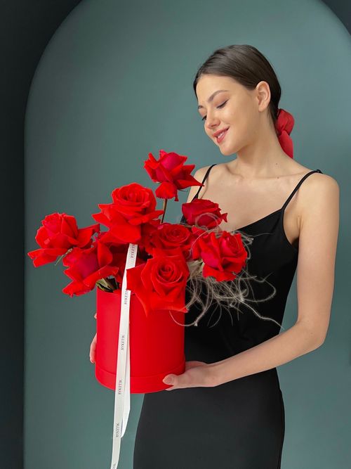 Free Woman in a black dress holding vibrant red roses, smiling. Stock Photo