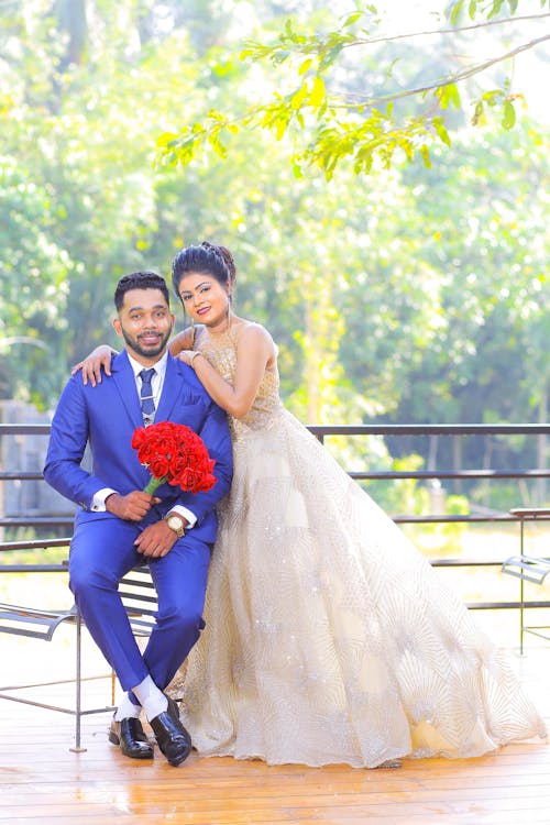 Free Man in Blue Suit Holding Bouquet of Flowers Beside Woman in White Wedding Gown Stock Photo