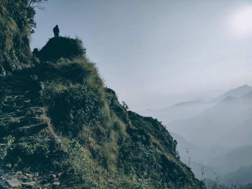 Free Silhouetted figure on a mountain ridge in Kaule, Nepal, with misty hills in the background. Stock Photo