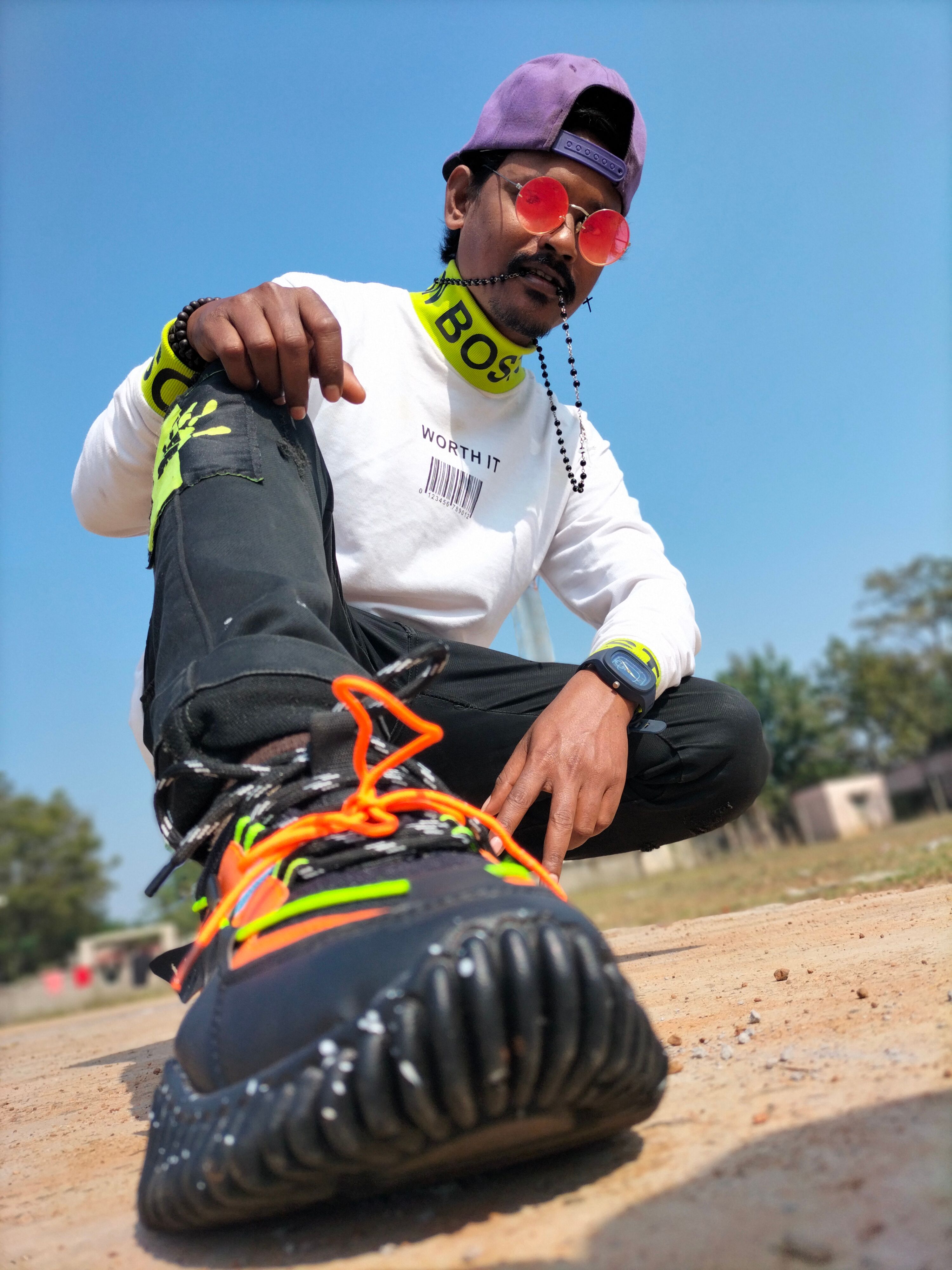 Man wearing bright sneakers with neon details poses confidently outdoors.