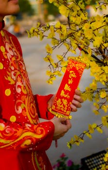 Close-up of a person in vibrant traditional clothing holding a Tet New Year decoration in Vietnam.