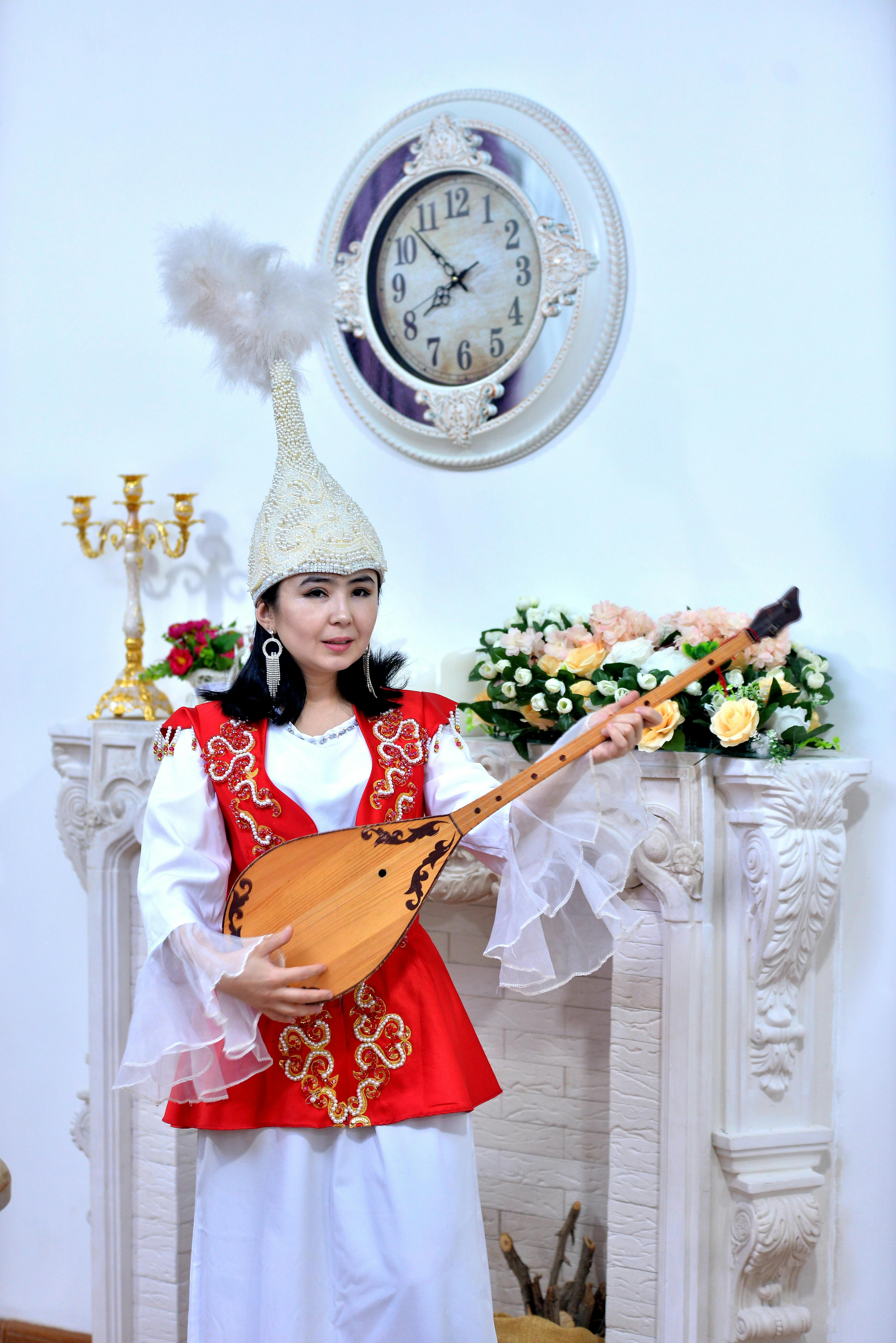 A woman in traditional attire playing a stringed instrument in an elegant indoor setting.