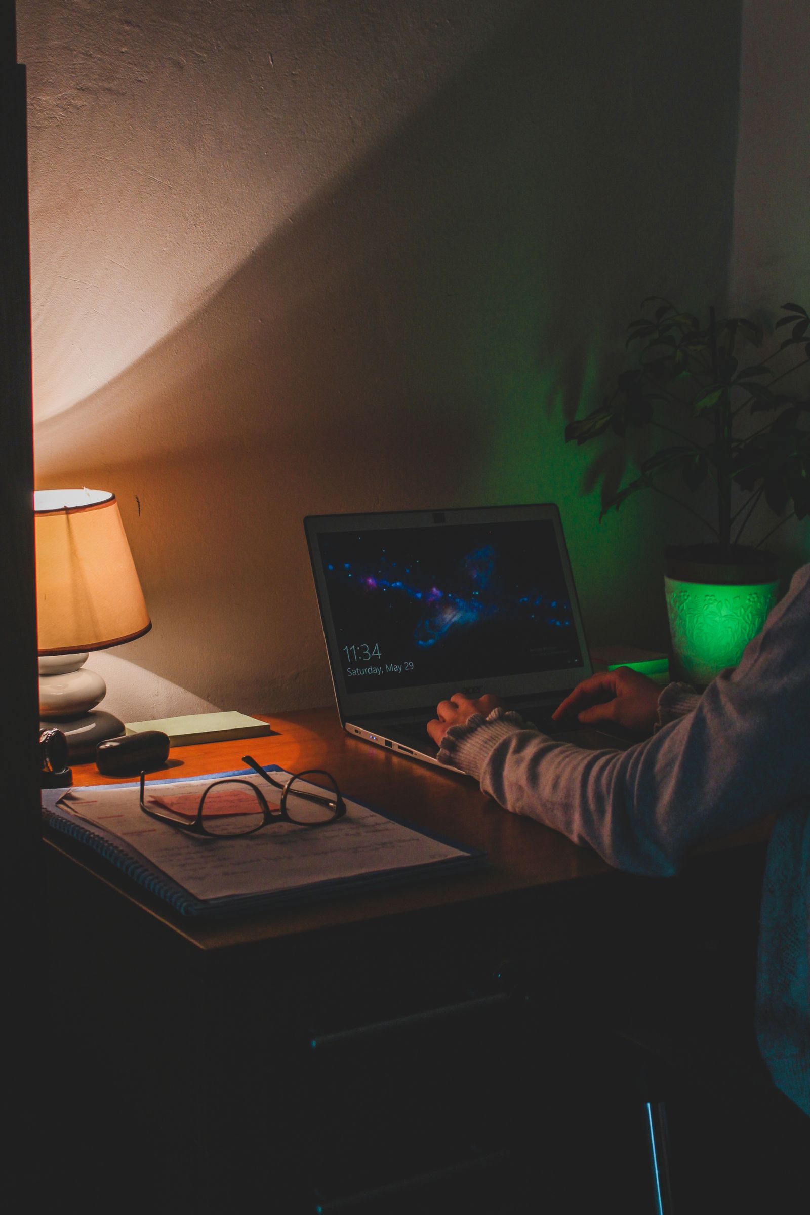 A person working on a laptop in a dimly lit home office