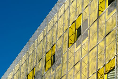 Free Modern architectural facade with yellow windows and blue sky background. Stock Photo