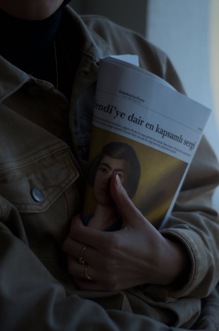 Person In Jacket Holding Magazine In Hand