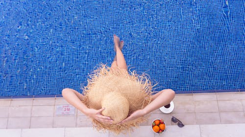 Free A Person Wearing Straw Hat while Sitting on the Edge of the Pool  Stock Photo