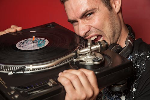 A Man About to Bite the Turntable he is Holding