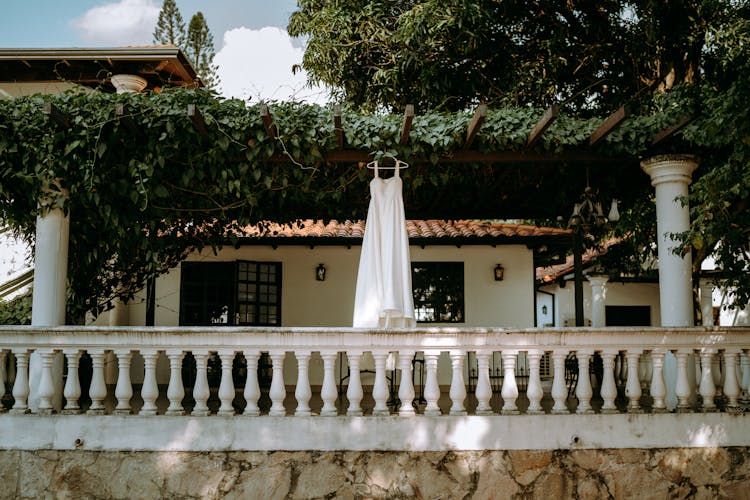 A White Dress Hanging On The Trellis