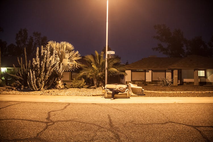 Person Lying Down On Sofa Near Road During Night Time 