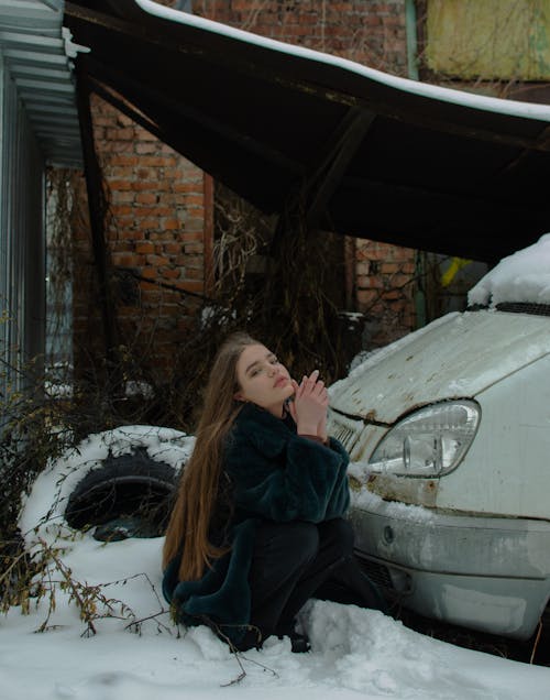 Petty Woman Squatting Beside an Abandoned Car