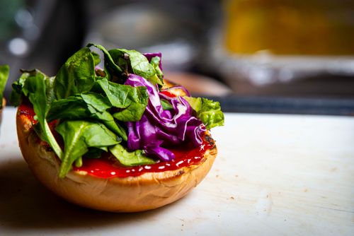 Free A vibrant close-up of a sandwich with fresh spinach, red cabbage, and ketchup on a bun. Stock Photo