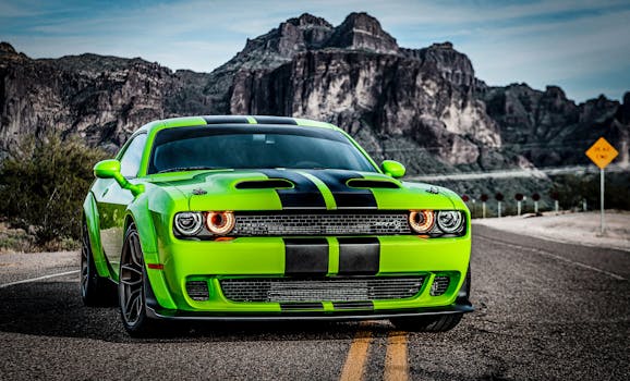A neon green Dodge Challenger on a scenic road with rocky mountains in the background.