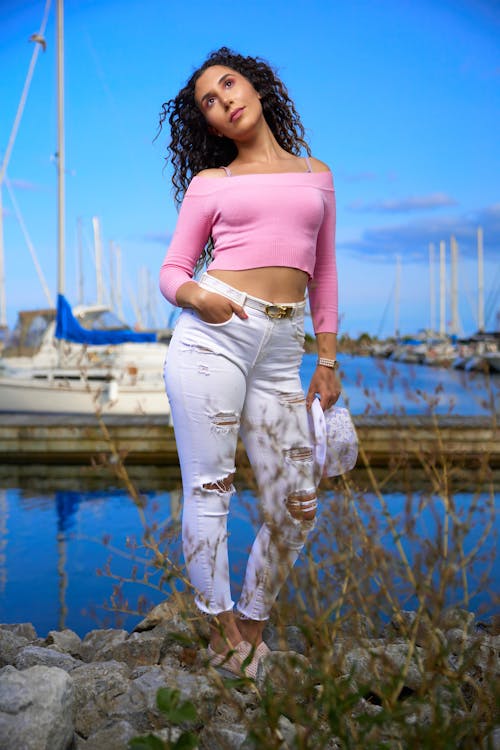 Free Woman in Pink Off Shoulder Long Sleeves and White Pants With Hand in Pocket Looking Up Stock Photo