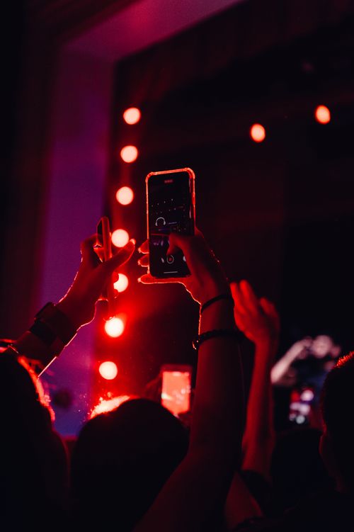 Free Vibrant concert scene with audience filming the performance on mobile phones under dramatic lighting. Stock Photo