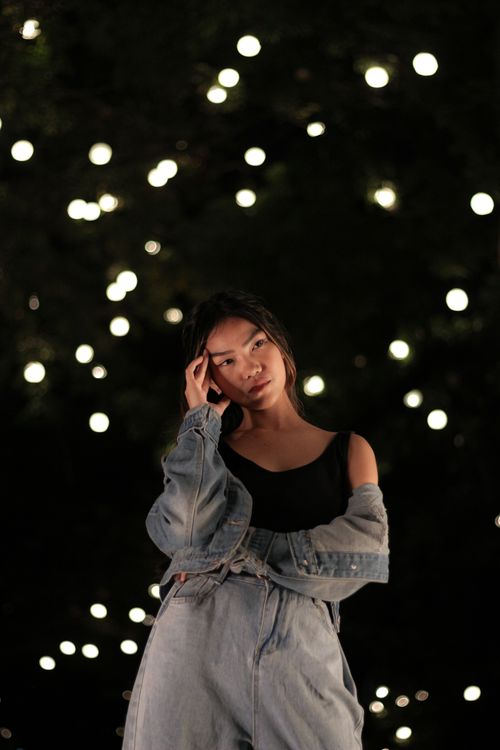 Free Portrait of a stylish woman in denim jacket surrounded by bokeh lights at night. Stock Photo