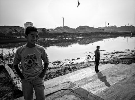 Captivating black and white portrait of boys by a pond in industrial Bangladesh.