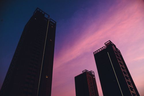 Free Silhouetted skyscrapers stand against a vibrant twilight sky with hues of pink and purple. Stock Photo