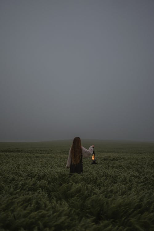 Woman on the Grassy Meadow with a Kerosene Lamp 