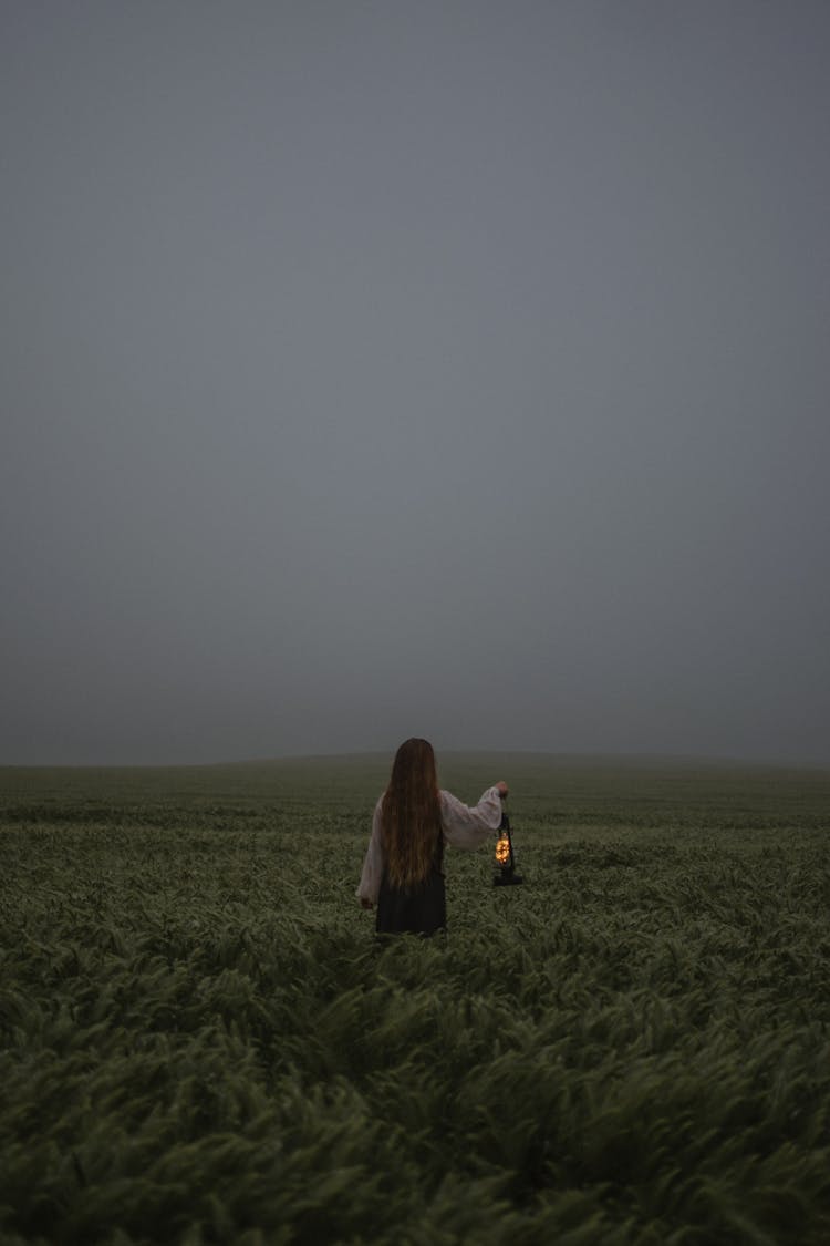 Woman On The Grassy Meadow With A Kerosene Lamp 