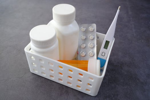 Healthcare basket with medication bottles, pills, and thermometer on a dark surface.