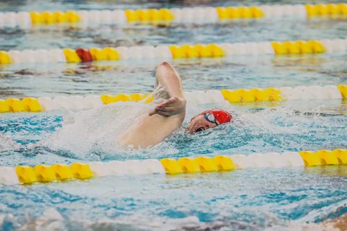 Free A swimmer in a red cap competes in freestyle swimming at an indoor pool with bright lane markers. Stock Photo
