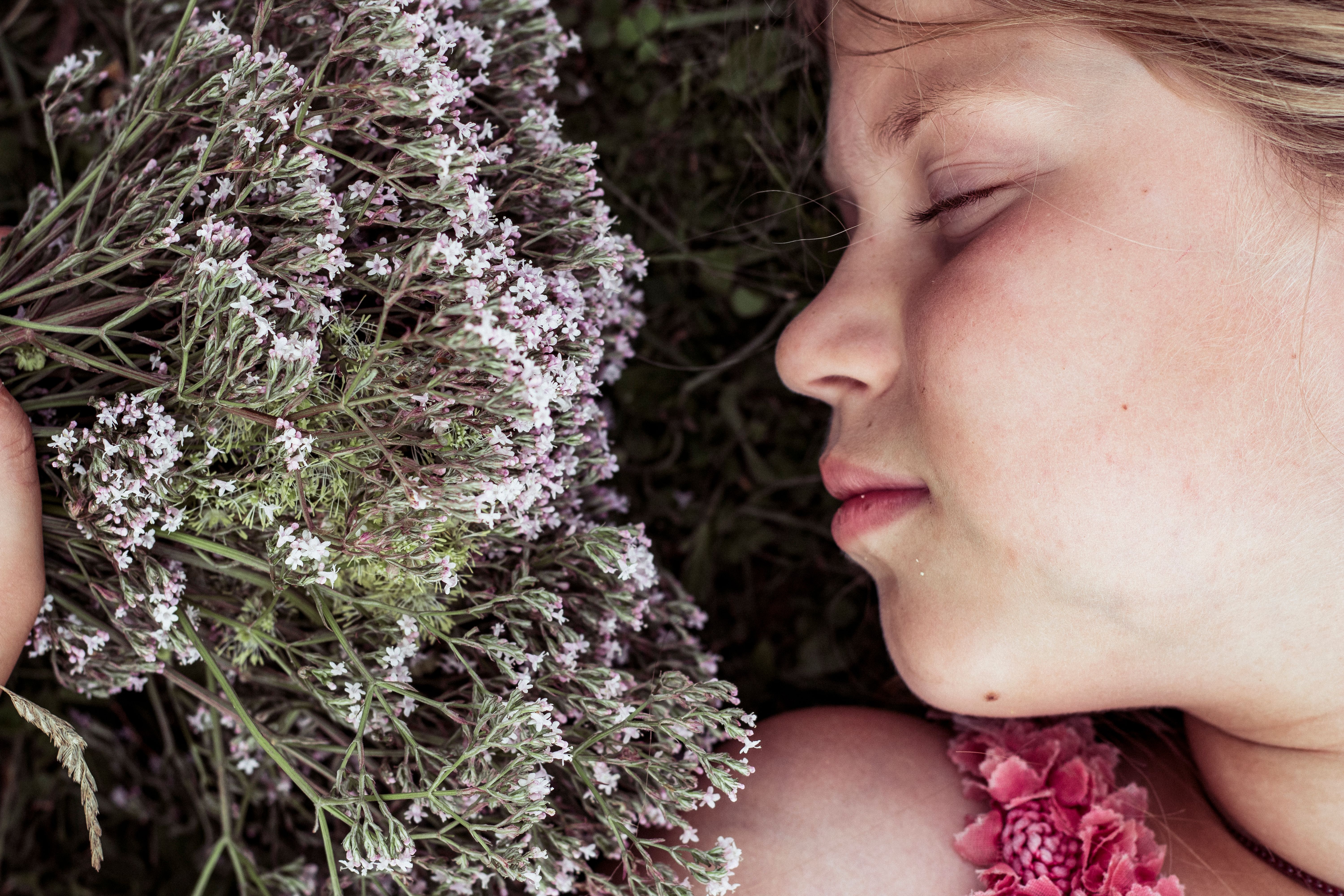 A young girl with her eyes closed rests among blooming valerian flowers, radiating tranquility. - Evidence evidence guide for valerian sleep onset randomized trial