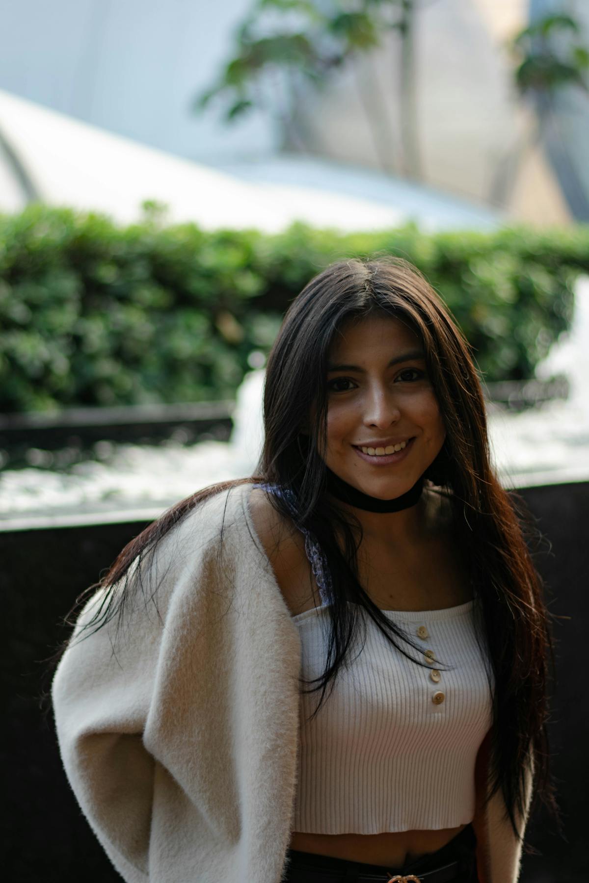 Donna con top bianco e cardigan beige in posa neutra