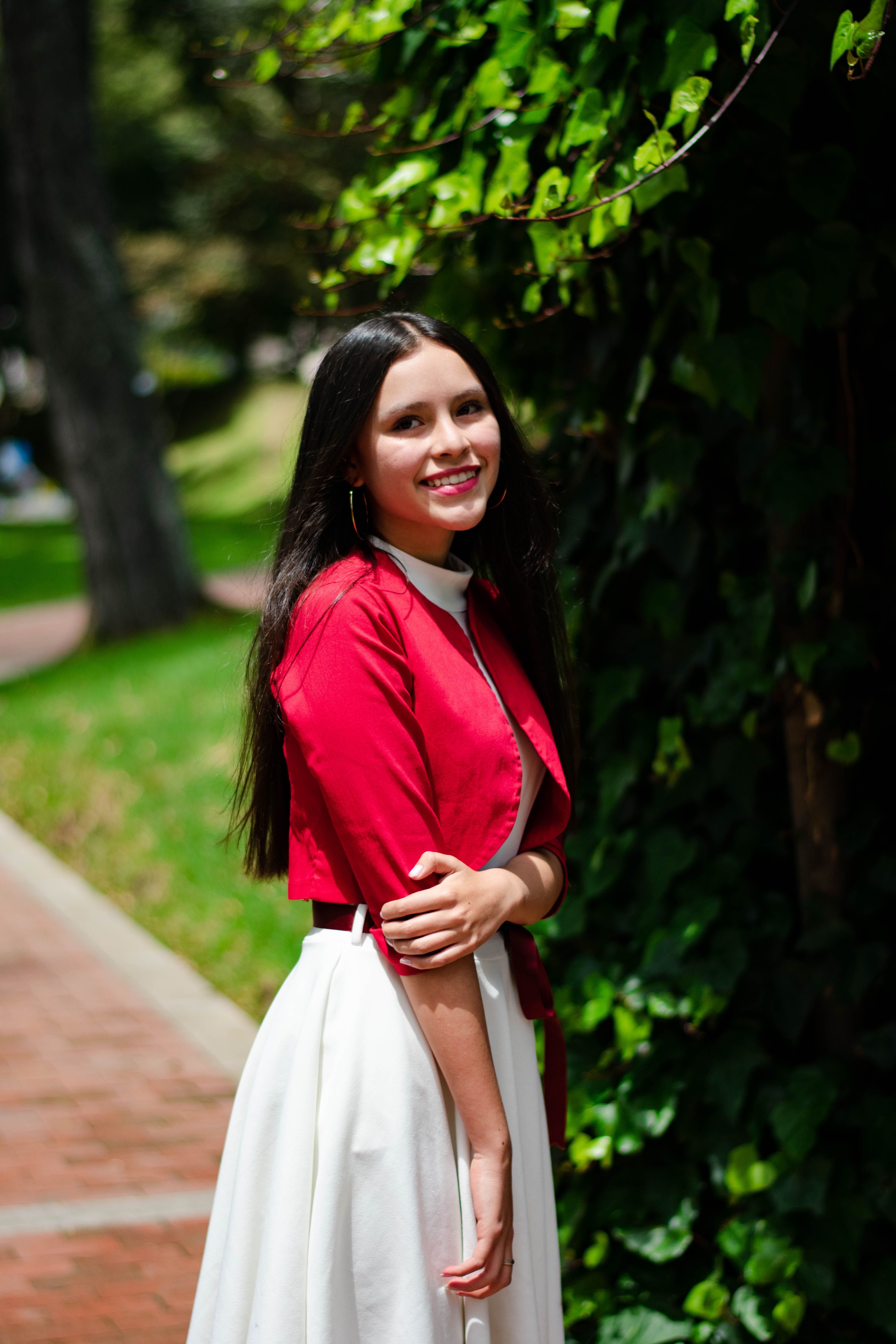 Smiling Woman in White Dress Standing near a Tree · Free Stock Photo