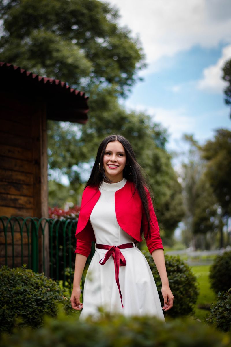 Woman in a white dress and red blazer smiling