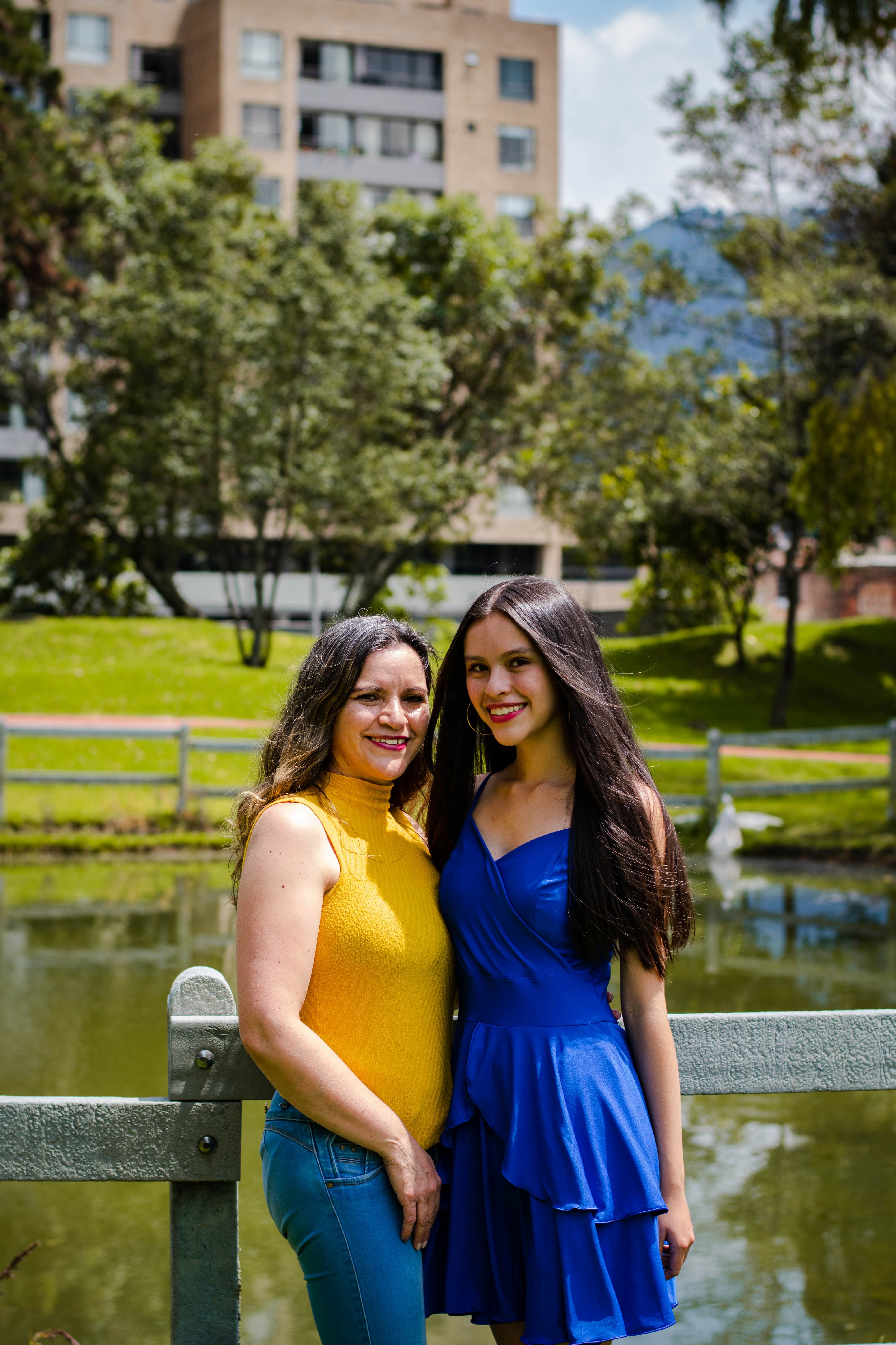 Two women enjoying a sunny day by the park pond, showcasing friendship and happiness.