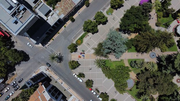 Top-down drone view of city park with trees and roads.