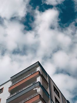 Low-angle shot of a modern apartment building with a cloudy sky background.