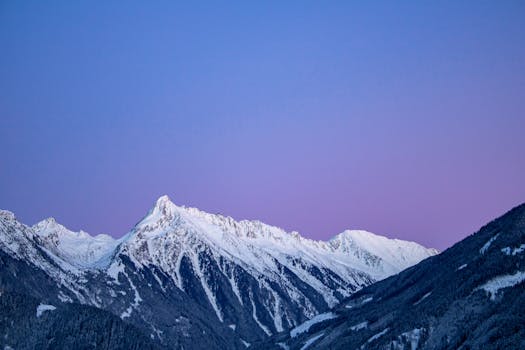 Beautiful view of snow-covered mountains under a clear blue sky at dusk, perfect for nature photography.