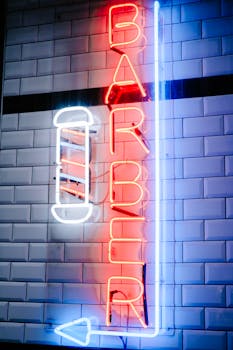 Bright neon barber sign illuminated against a tiled wall setting.