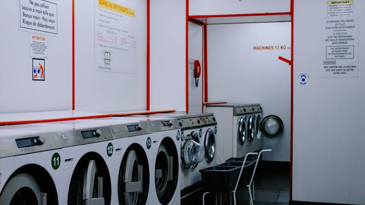 Industrial Washing Machines Lined Up Under Wall