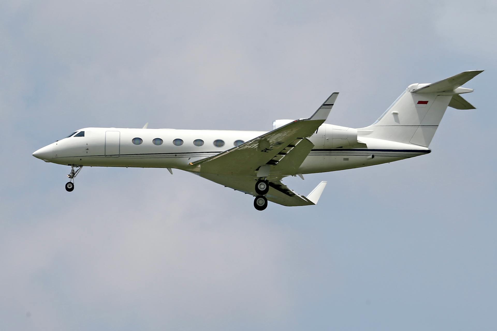 Elegant private jet flying mid-air against a clear blue sky.
