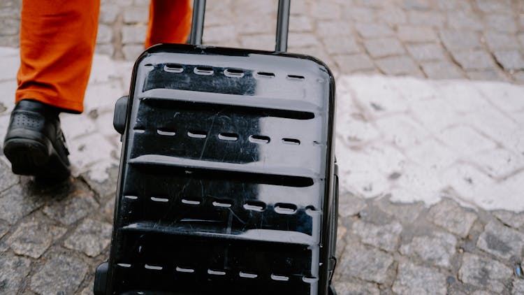 Person Pulling A Black Trolley Bag