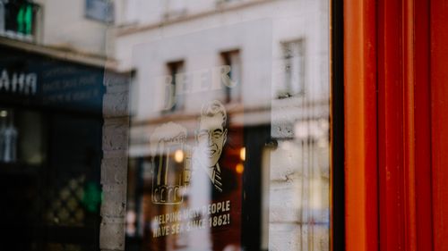 Free Close-up of a window reflection showing a vintage beer sign in an urban setting. Stock Photo